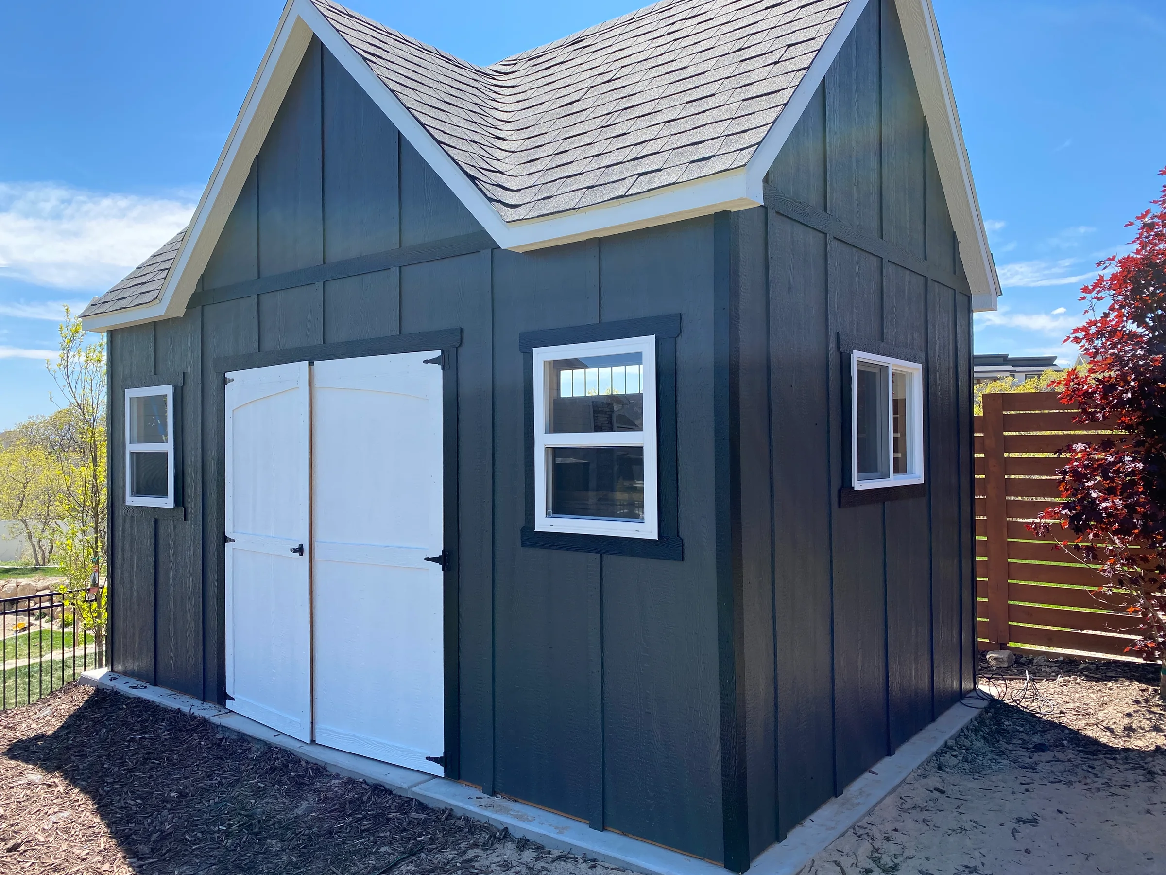 Blue-gray painted shed siding with white doors and window trim.