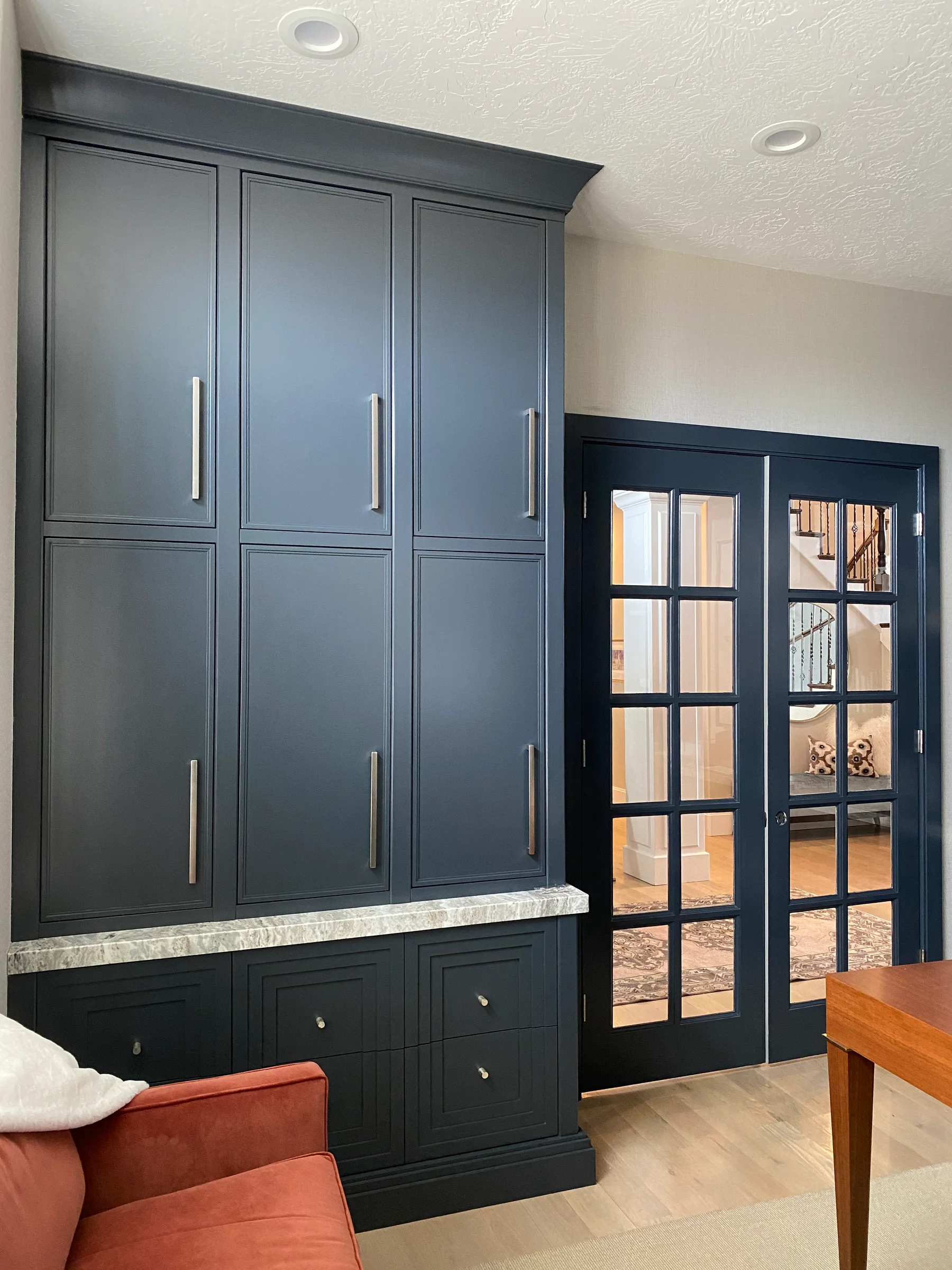 Dark floor-to-ceiling painted cabinetry beside a glass-paneled door.