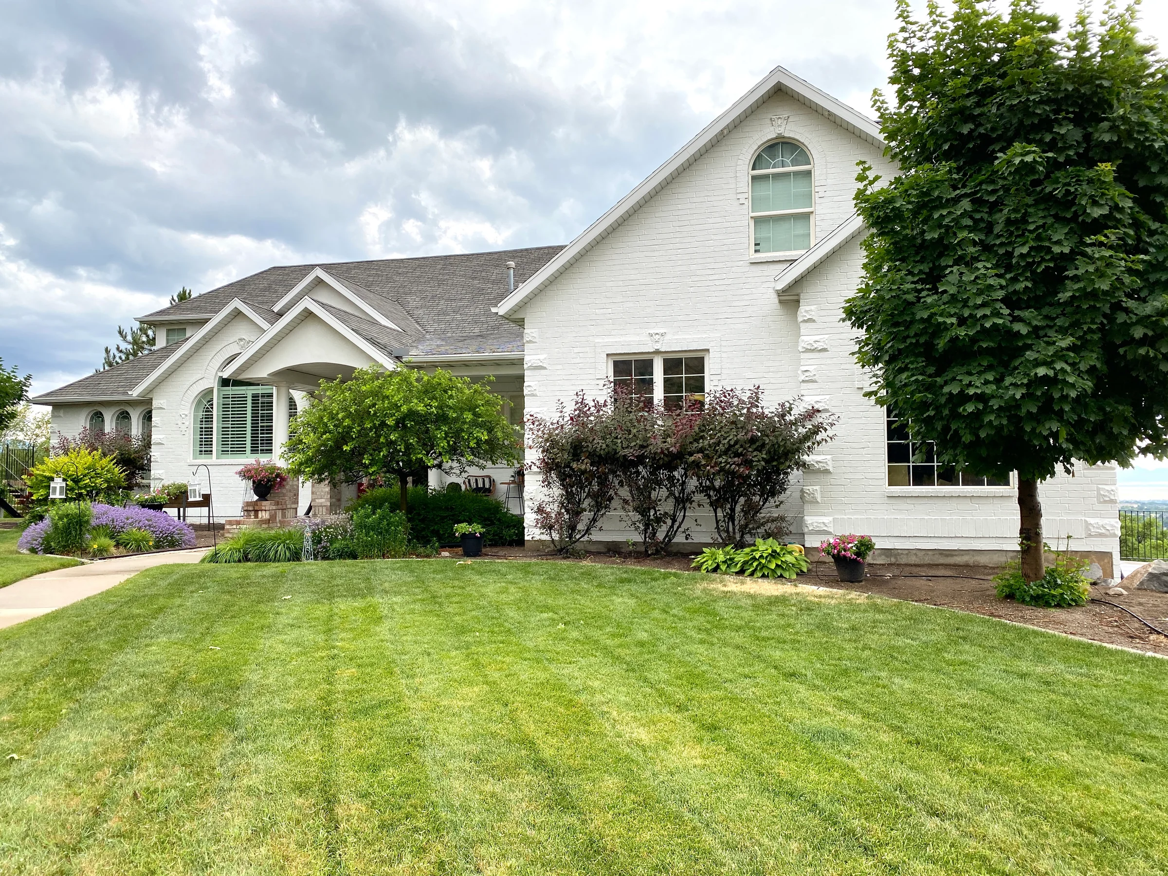 Light painted home exterior with white trim, lawn and mature landscaping.