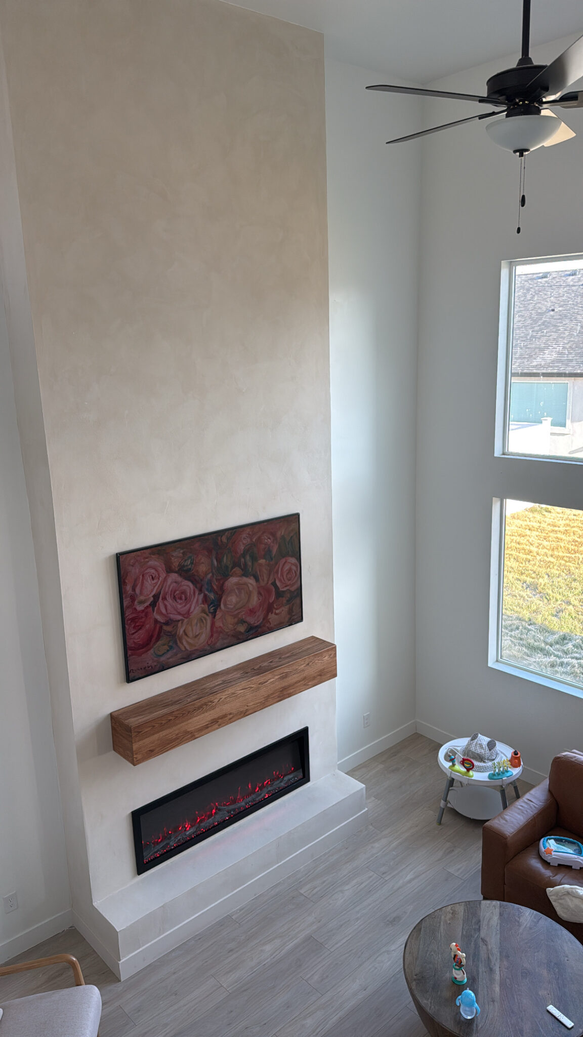 Warm limewash finish on a tall fireplace wall with a wood mantel