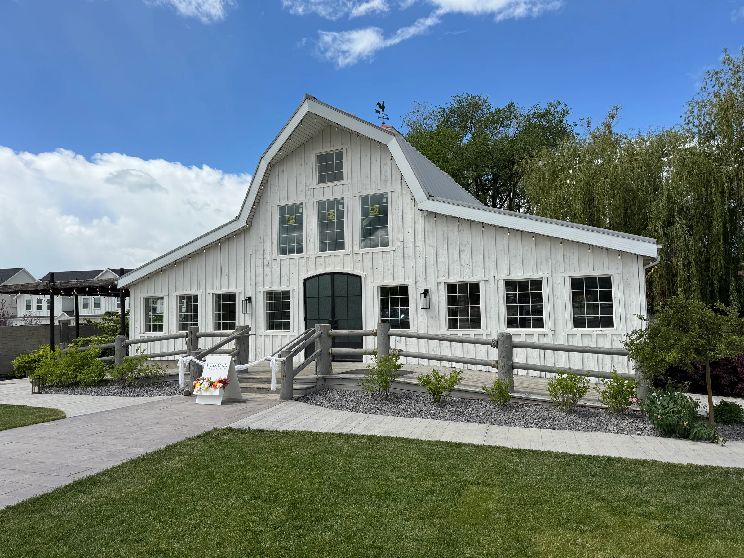White barn exterior with black-framed windows and a landscaped lawn.