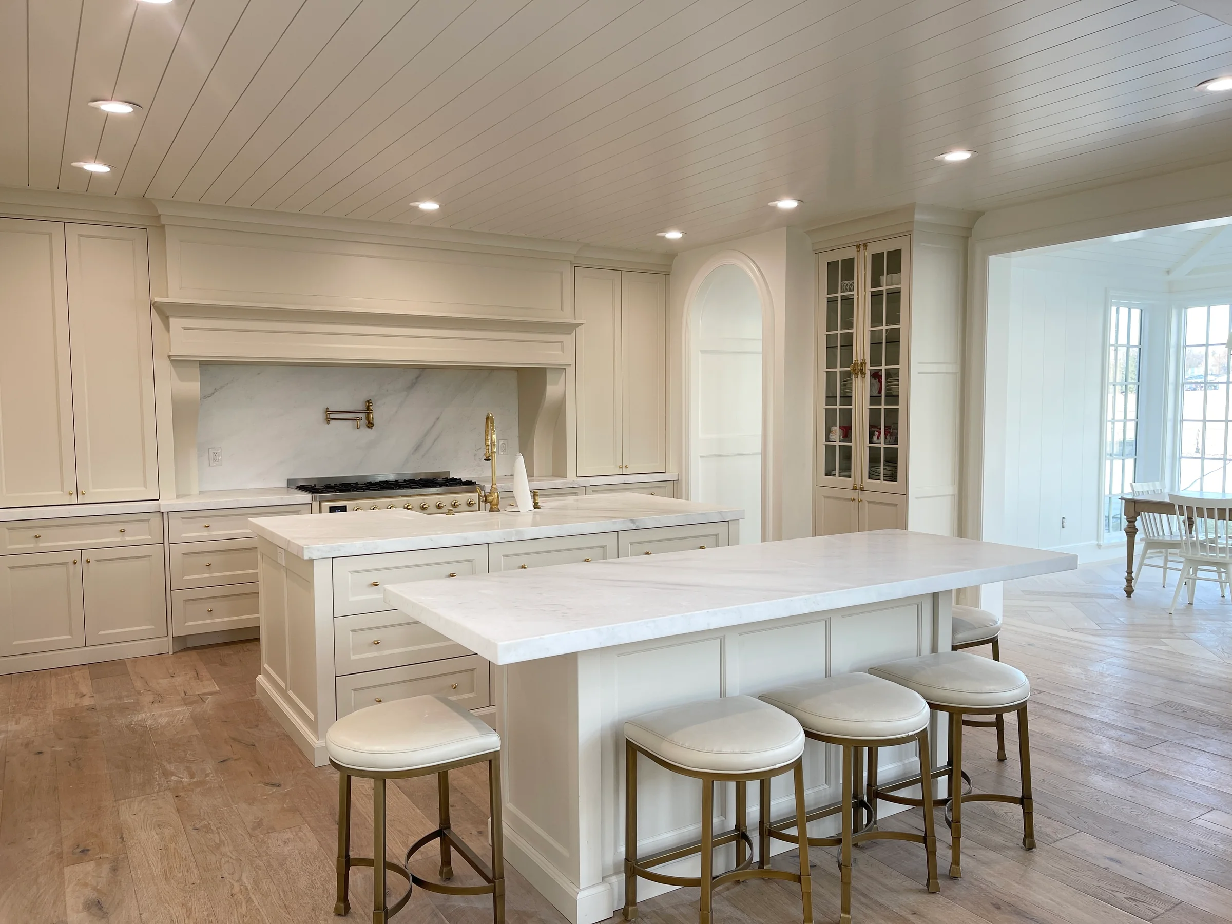 Bright kitchen with white painted cabinets, a pale island and recessed lighting.