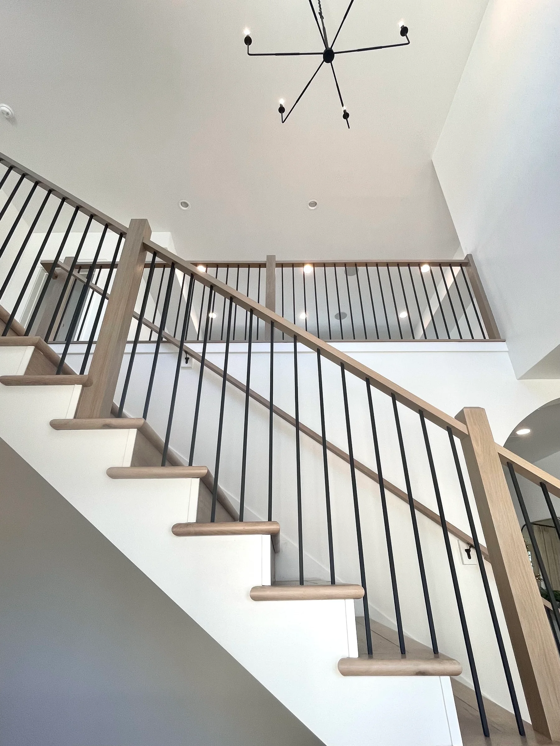 White staircase walls and trim beside black metal handrails.
