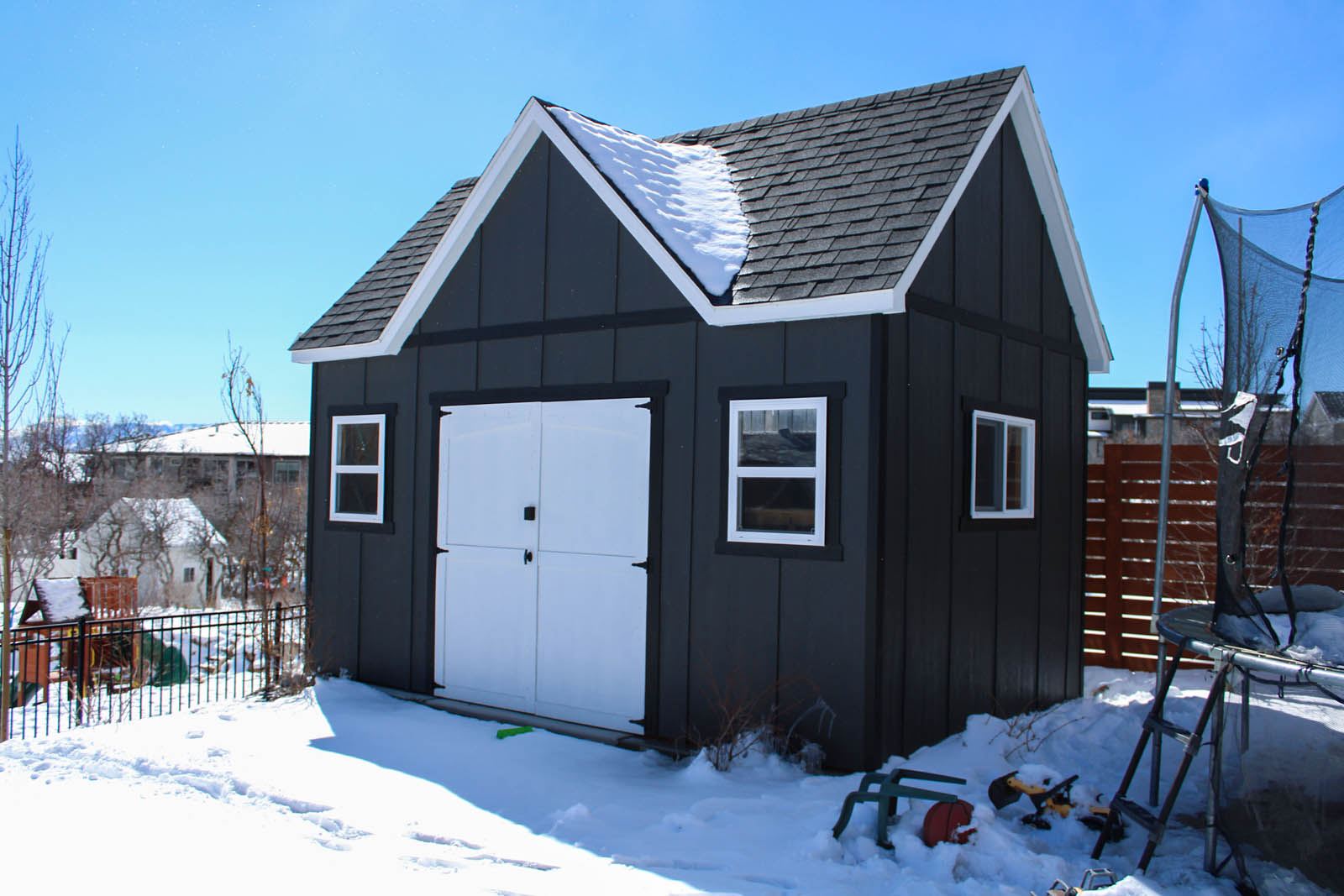 Dark detached garage with white trim and snow