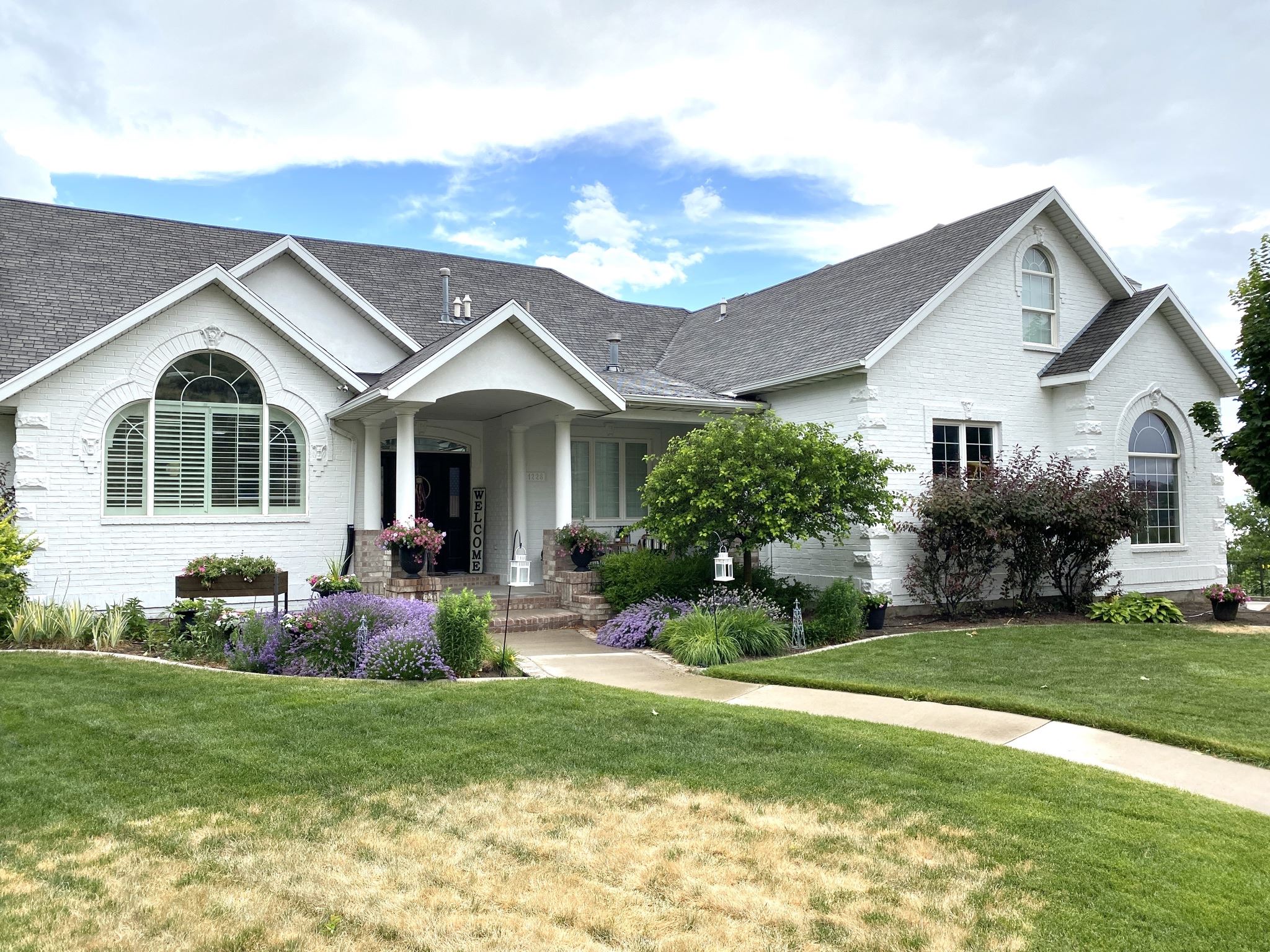 White home exterior with gray roof and shrubs