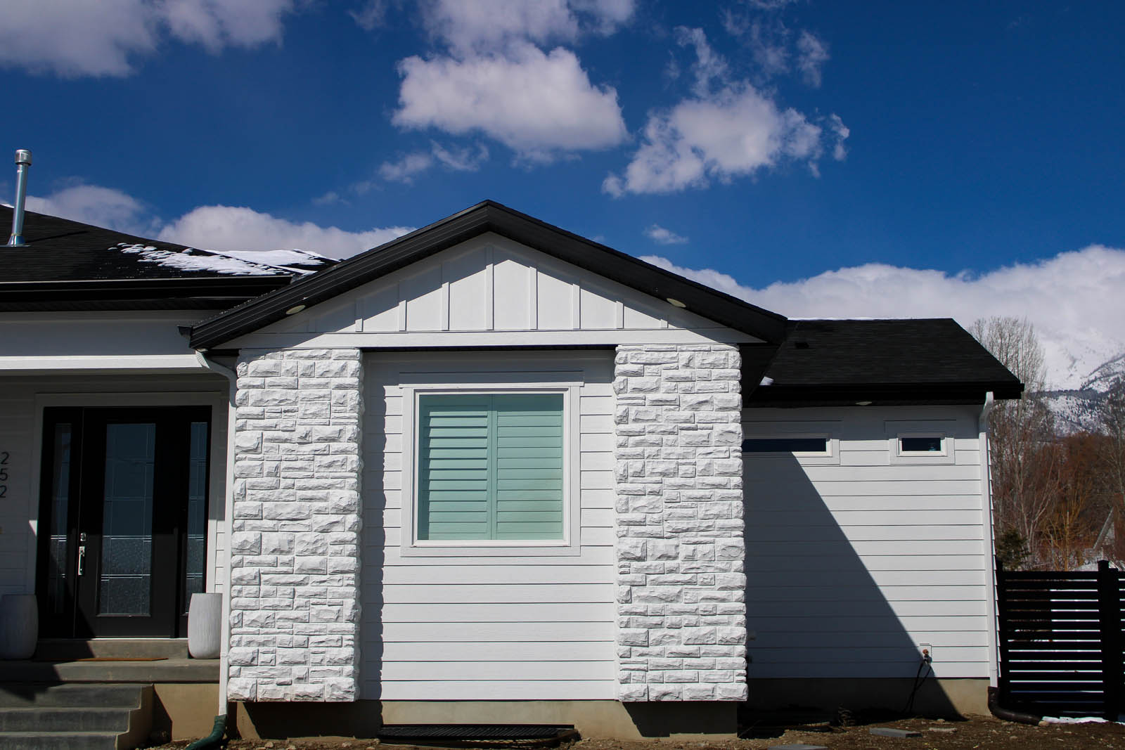 White siding and stone accent wall outside a home